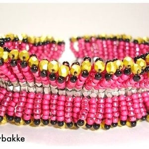 May include: A pink, black, gold, and silver beaded bracelet with a ruffled design.