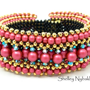 Peut inclure: Un bracelet en perles multicolores avec un schéma de couleurs or, rose et bleu. Le bracelet est fait de petites perles rondes et a un design tissé texturé.