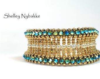 May include: A gold and blue beaded bracelet with a row of white pearls in the center. The bracelet is made with small, round beads and has a delicate, elegant design.