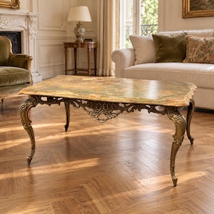 May include: A rectangular coffee table featuring a polished green and brown marble top with natural veining. The table is supported by four ornate, curved legs made of antique gold-toned metal with intricate scrollwork and decorative carvings.