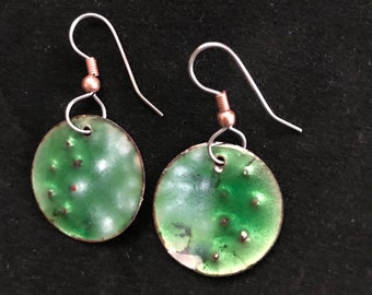 May include: A pair of green and white enamel earrings with silver hooks. The earrings are round and have a speckled design.