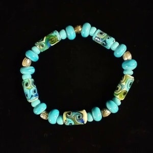 Bransoletka z ciemnoturkusowych, wirujących pawich koralików Lampwork.
