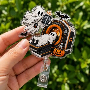 May include: An acrylic badge reel featuring a white ghost wearing a Rad Tech ID badge and holding an X-ray, a second ghost lying on a radiology scanner labeled Radiology, a jack-o'-lantern bucket with a medicine vial, and two black bats.