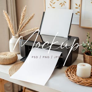 May include: A black printer with a white sheet of paper coming out of it. The printer is on a white table with a wicker coaster and a candle on a wicker mat. There are dried flowers in a vase and a potted plant in the background.