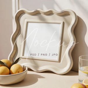 Könnte beinhalten: Ein beigefarbener Bilderrahmen mit gewelltem Rand und dem Wort "Mockup" in der Mitte. Eine Schale mit Zitronen und ein Glas Wasser mit Zitronenscheiben befinden sich im Vordergrund. Der Rahmen ist etwa 30 cm breit.