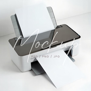 May include: A white and gray printer with a sheet of white paper in the input tray and another sheet being printed. The printer has the word "Mockup" overlaid on the image, along with "PSD / PNG / JPG".
