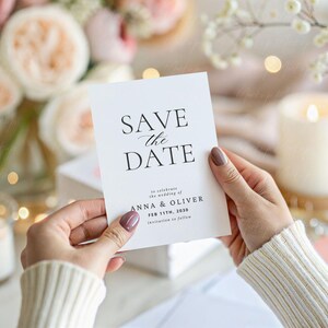 May include: A white save the date card with black calligraphy that reads "Save the Date" and features the names "Anna & Oliver" and the date "Feb 15th, 2030".