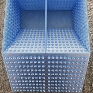 May include: A light blue plastic organizer with two compartments. The organizer has a textured surface with small bumps.