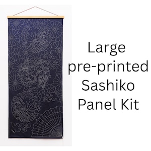 May include: A large navy blue fabric panel for Sashiko embroidery featuring white pre-printed patterns of circular floral motifs, clouds, and a folding fan. The panel is suspended from a light-colored wooden hanger with a thin brown cord.