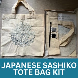 May include: A natural canvas tote bag with a blue and white embroidered design. The bag is part of a Japanese Sashiko tote bag kit, which includes thread, a pencil, and instructions. The kit is packaged in a cardboard box.