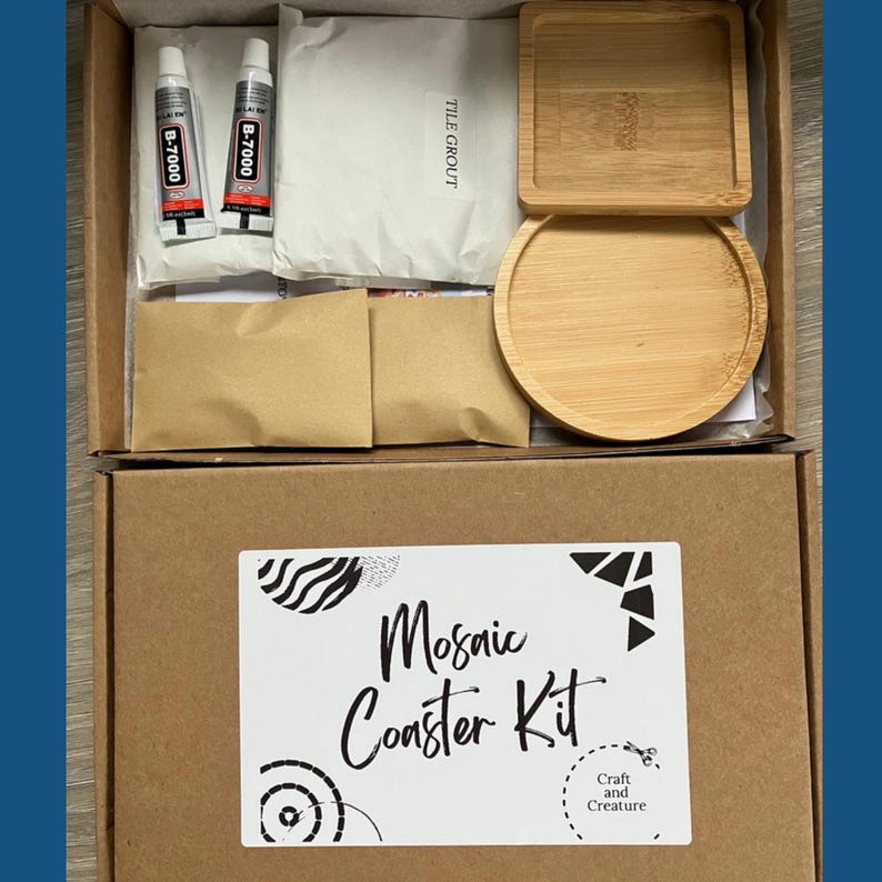 May include: A mosaic coaster kit in a cardboard box. The kit includes two tubes of B-7000 glue, a package of tile grout, two small brown paper packets, and two bamboo coasters. The box has a label that reads "Mosaic Coaster Kit" and "Craft and Creature."
