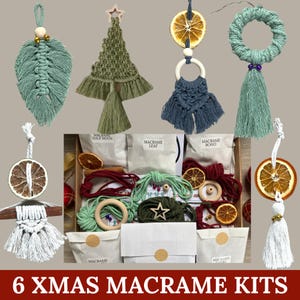 Peut inclure: Ensemble de kits de Noël en macramé, présentant des ornements faits à la main en vert, bleu et blanc. Les kits comprennent des motifs de feuille, d'arbre et de couronne, avec des tranches d'orange séchées et des éléments en bois.