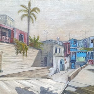 May include: An oil painting depicting a street scene with a tall palm tree, a pink building on the left, and blue structures in the background. A white wall features a red letter A, while a red letter B is visible on a gate near the right side.