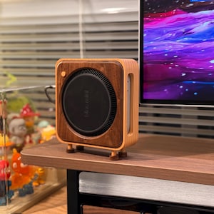 Può includere: Un computer Mac mini in una custodia di legno con la scritta "Mac mini" sul davanti. Il computer è appoggiato su una scrivania di legno.
