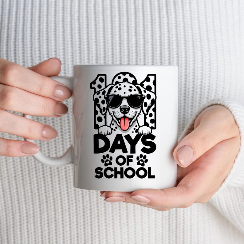 K&ouml;nnte beinhalten: Wei&szlig;e Keramik-Tasse mit einem Dalmatiner, der eine Sonnenbrille tr&auml;gt, und dem Text "101 DAYS OF SCHOOL" in Schwarz. Der Hund hat schwarze Flecken und eine rosa Zunge. Pfotenabdr&uuml;cke sind darunter.