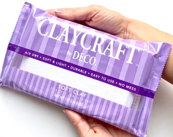 Può includere: Una confezione di argilla morbida Claycraft by Deco, di colore viola e bianco. La confezione riporta la scritta "Air Dry, Soft & Light, Durable, Easy to Use, No Mess". La confezione riporta anche "Soft Clay" e "クレイクラフト デコ ソフトクレイ" in giapponese. La confezione riporta "Net Wt 137 g (4.8 oz)".