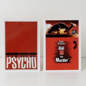 May include: Two framed film posters. The left poster has a red background with the word "PSYCHO" in white. The right poster has a red background with the text "Alfred Hitchcock's dial M for Murder" and a phone illustration.