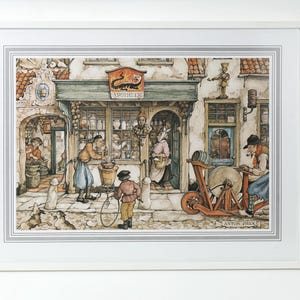 May include: A framed watercolor print depicting a bustling apothecary shop scene. The artwork features detailed figures, a shop sign with text, and a variety of architectural elements. The print is framed in a white border.