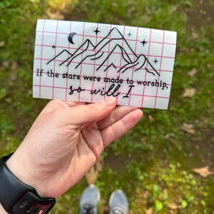 May include: A white sticker with a black line drawing of mountains, a crescent moon, and stars. The text "If the stars were made to worship, so will I" is written below the drawing.