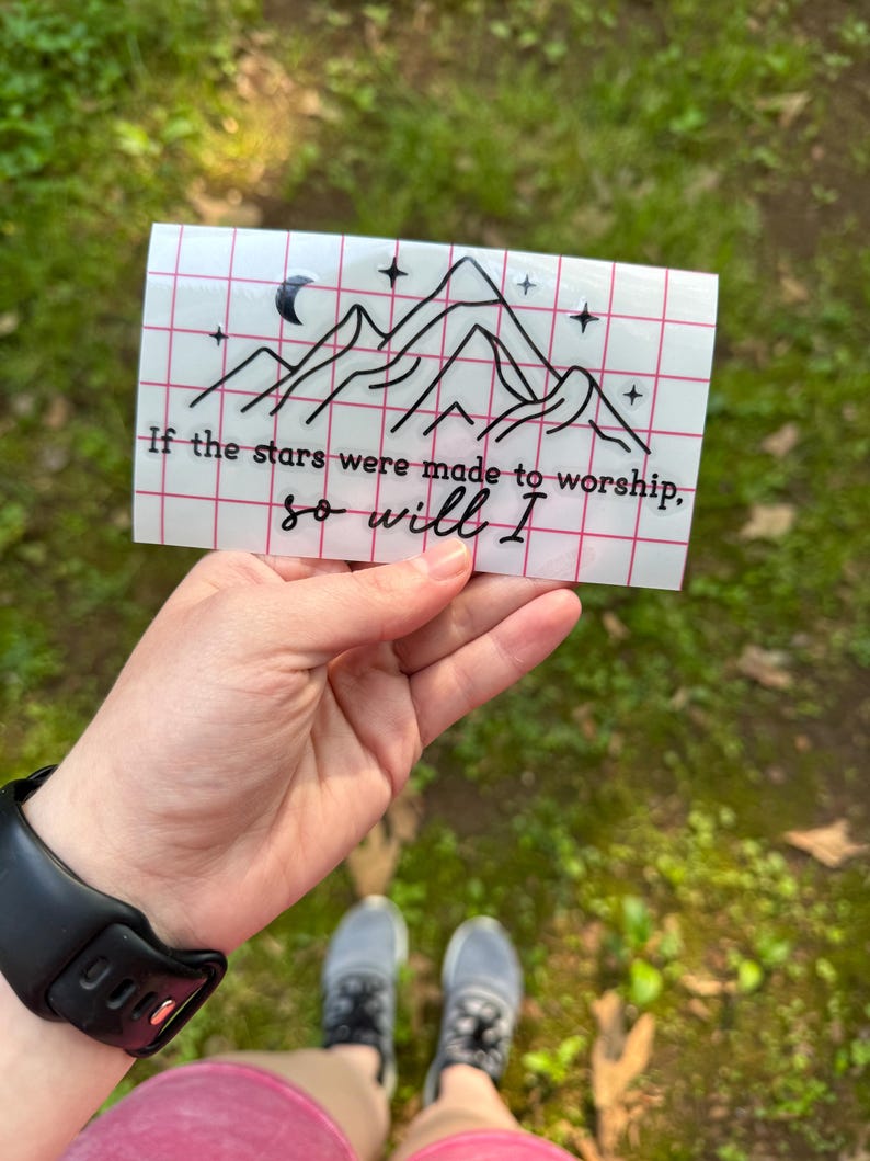 May include: A white sticker with a black line drawing of mountains, a crescent moon, and stars. The text "If the stars were made to worship, so will I" is written below the drawing.