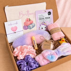May include: A gift box containing a personalized canvas pouch, a grape seed facial mask, a wish bracelet, a fuzzy purple sleep mask, a Lip Smacker balm, a bath bomb, a mini spa cloth, a yellow rubber duck, two satin scrunchies, and a fuzzy headband.