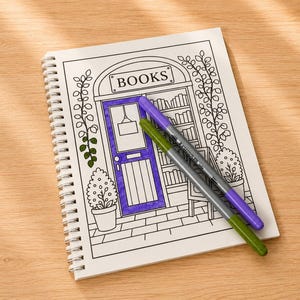 Puede incluir: Una p&aacute;gina de libro para colorear con espiral que presenta una ilustraci&oacute;n de l&iacute;neas de la fachada de una librer&iacute;a con la palabra BOOKS impresa sobre la puerta. La puerta est&aacute; coloreada en morado y dos rotuladores, uno morado y otro verde, descansan.