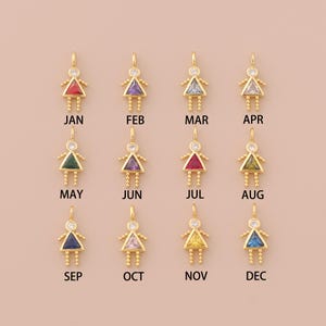 May include: Twelve gold charms shaped like a girl with a different colored gemstone in the center of each charm. The charms are labeled with the months of the year, January through December.