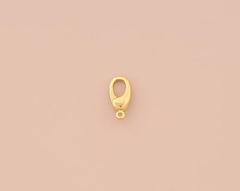 以下が含まれることがあります： 滑らかで丸みを帯びた仕上げの金色の金属製ロブスタークラスプ。このクラスプは、ネックレス、ブレスレット、その他のジュエリープロジェクトに使用される一般的なジュエリーファインディングです。