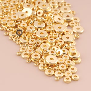 May include: A large pile of gold-colored metal spacer beads. The beads are round with a hole in the center. They are perfect for jewelry making.