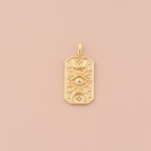 May include: Gold pendant necklace featuring a rectangular charm with an eye, sun, and moon design. The charm is detailed with small stars.