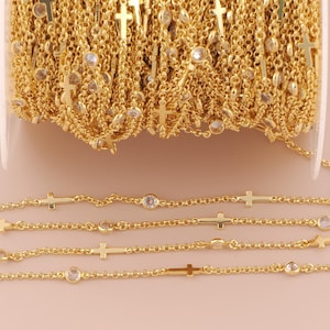 Puede incluir: Cadena dorada con detalles de cruces y cristales. La cadena se muestra en rollo y extendida, resaltando el diseño. Las cruces son pequeñas y espaciadas uniformemente, con cristales transparentes intercalados.