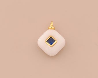 May include: A white, diamond-shaped pendant with a gold-coloured bail. The centre features a square, deep blue gemstone set in a gold frame. The pendant is likely for a necklace or bracelet.