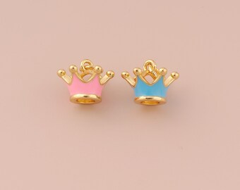 May include: Two gold-colored crown charms with enamel accents. One charm is pink and the other is blue.