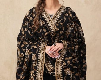 May include: A black shawl featuring intricate gold and silver floral embroidery throughout the fabric. The garment has a wide, decorative border with detailed metallic stitching along the edges, draped over the shoulders and upper body.