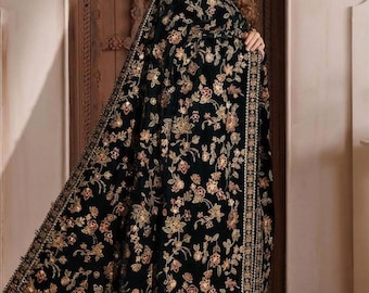 May include: A long, black velvet shawl featuring intricate, multi-colored floral embroidery in shades of gold, pink, and green. The garment has a high collar, long sleeves, and a wide, decorative border with metallic detailing along the edges.