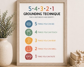 May include: A framed print with the text "5-4-3-2-1 GROUNDING TECHNIQUE" in a variety of colors. The print lists steps to identify things you can see, touch, hear, smell, and taste. The frame is a light brown color.