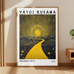 May include: Framed art print featuring a yellow road leading to a bright sun in a dark, dotted sky. The print is labeled "YAYOI KUSAMA" and "Modern Art 1944". The artwork is displayed in a room with wooden accents and a small side table.