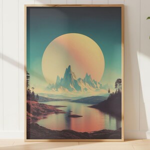 May include: A framed landscape art print featuring a large, glowing sun over a mountain range and a lake. The color palette includes shades of blue, orange, and pink, creating a serene and atmospheric scene. The artwork is displayed on a light wood floor.