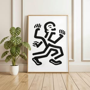 Puede incluir: Impresi&oacute;n art&iacute;stica abstracta en blanco y negro que representa una figura estilizada con m&uacute;ltiples extremidades en movimiento. La obra de arte est&aacute; enmarcada en un marco de madera y colocada contra una pared blanca. Una planta en maceta est&aacute; en primer plano.