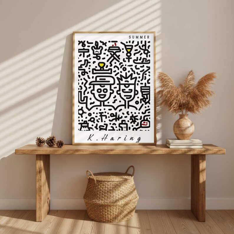 May include: A framed art print featuring a black and white abstract design with the word "SUMMER" at the top. The artwork includes two stylized figures and the artist's signature, "K. Haring". The print is displayed on a wooden bench.