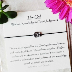 May include: A black cord bracelet with a silver owl charm. The card reads "The Owl Wisdom, Knowledge & Good Judgement. The owl was a symbol for the Greek goddess of wisdom and strategy, Athena. The owl was a symbol of higher wisdom and was known as a guardian. It represents a connection with wisdom, good judgement and knowledge as well as insight and intuition. Adjustable Cord Bracelet."