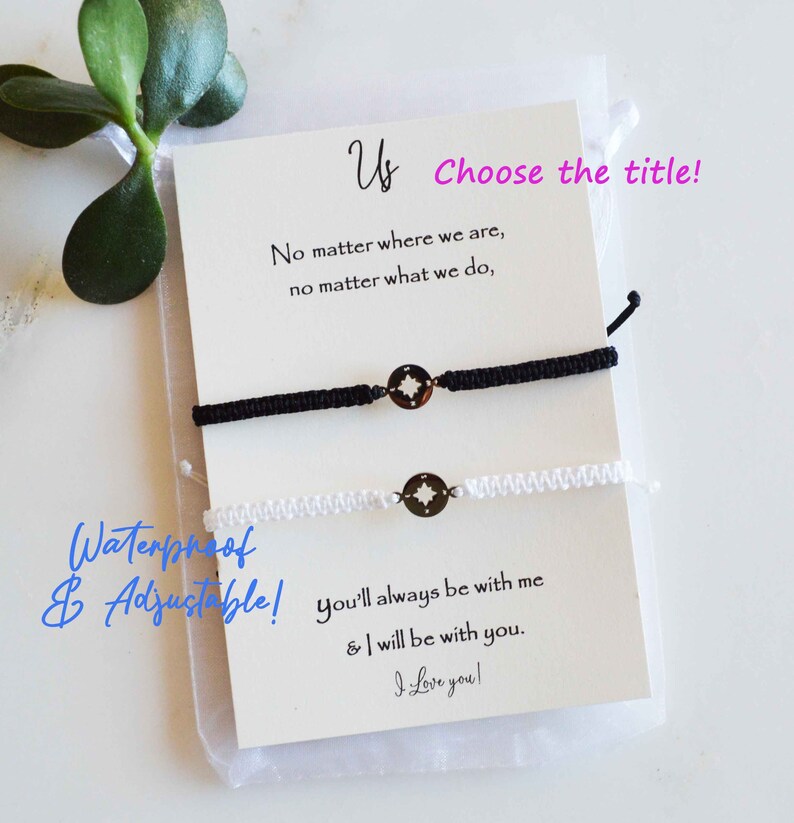 May include: A pair of matching black and white friendship bracelets with compass charms, displayed on a card with the text "Us". The card also includes the phrases "No matter where we are" and "I love you!"