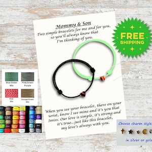 May include: Two matching black string bracelets with a heart charm. The bracelets are displayed on a white card with the text "Mommy & Son" and a message about the bracelets. The card also shows a variety of color options for the string and a selection of charms in silver or gold.