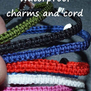 May include: A collection of waterproof charms and cords in various colors, including green, blue, black, red, white, and pink. The image shows a close-up of the braided cords, with the text "Waterproof charms and cord" at the top.