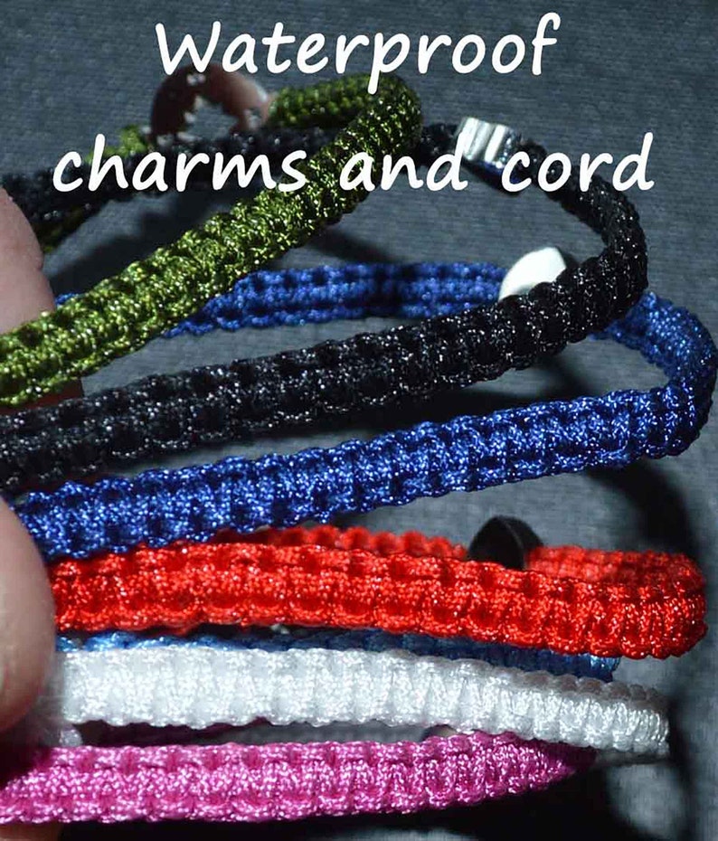 May include: A collection of waterproof charms and cords in various colors, including green, blue, black, red, white, and pink. The image shows a close-up of the braided cords, with the text "Waterproof charms and cord" at the top.