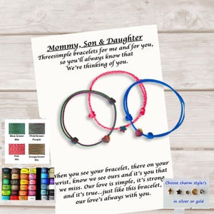 May include: Three adjustable cord bracelets in green, pink, and blue, each featuring a small charm. The bracelets are displayed on a white card with printed text reading Mommy, Son & Daughter and additional text about the bracelets.