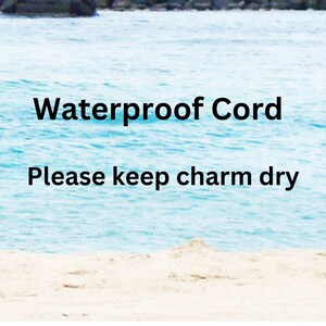 May include: Image of a serene beach scene with the ocean and sky in the background. The text "Waterproof Cord" is displayed in bold black letters, followed by "Please keep charm dry" in a smaller font.