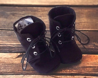 May include: A pair of black suede lace-up ankle boots with silver eyelets. The boots have a rounded toe and a short heel.