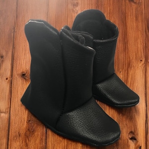 May include: A pair of black leather baby booties with a zipper on the side.