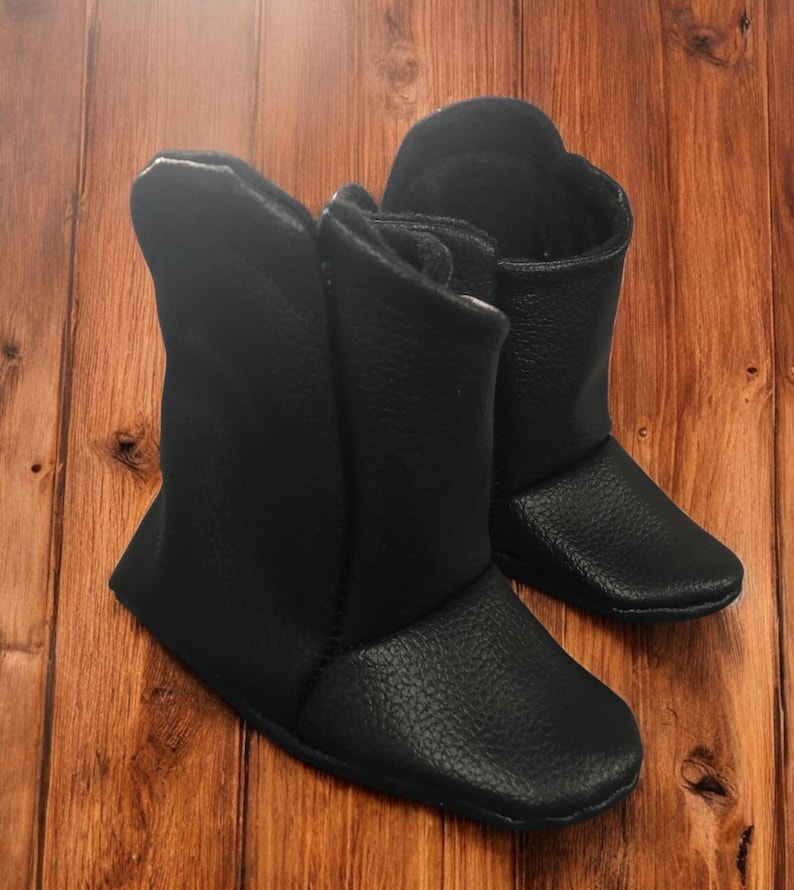 May include: A pair of black leather baby booties with a zipper on the side.